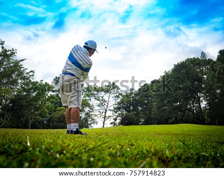 Blurred golfer swings golf ball on beautiful golf course
