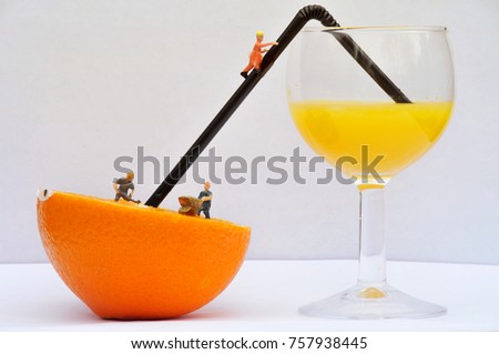 The Orange Juice Factory. Miniature men working hard on a giant industrial orange to squeeze all the juice into a glass to be shipped off across the world for humans to enjoy as orange juice. 
