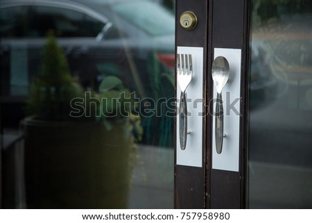 Close up on a restaurant entryway, with fork and spoon handles as door knobs