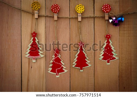The christmas tree and bell hang with rope and paper clip on wooden wall