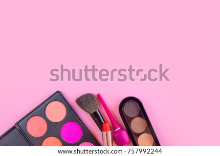 Lipstick, eye shadow, eyeliner cosmetics for girl on pink table background
