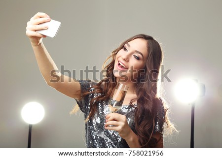 Young woman with glass of champagne making selfie