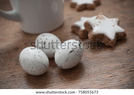 closeup of cup of coffee and stork eggs on wooden table background