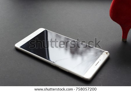 
the foot in the red shoe on the broken phone on the grey background