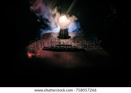 Music concept. Acoustic guitar isolated on a dark background under beam of light with smoke with copy space. Guitar Strings, close up. Selective focus. Fire effects. Surreal guitar
