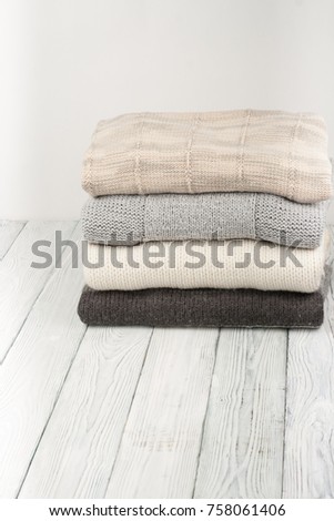 Knitted wool sweaters. Pile of knitted winter clothes on wooden background, sweaters, knitwear, space for text