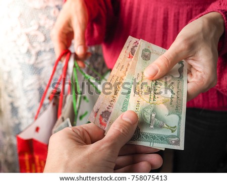 Customer pays dirham UAE bills cash while shopping.