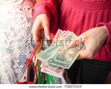 Customer pays dirham UAE bills cash while shopping.