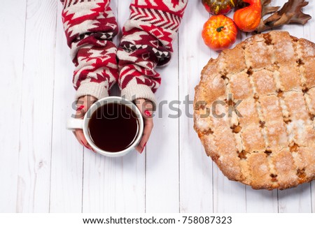 Apple pie and woman's hands holding cup of black tea with decoration for Christmas on wooden table