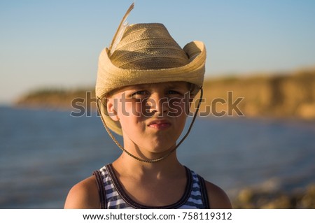boy in cowboy hat on the seashore