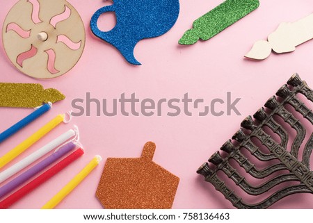 Image of jewish holiday Hanukkah with wooden dreidels (spinning top) , menorah (traditional Candelabra) candles, children's stickers glitter craft on pink background.Top view.Copy space for your text.