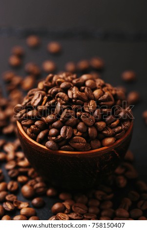 Roasted coffee beans scattered around. Gray stone background. Horizontal view