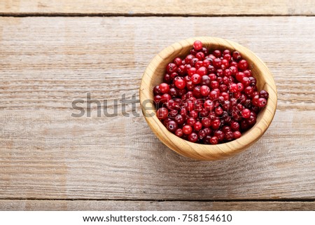 ripe cranberries in a plate, on a wooden background, organic vitamin product for strengthening immunity
