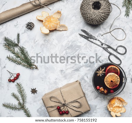 New Year composition, mulled wine cup, mandarins, fir branches, packing paper, cinnamon sticks, framed on a light rustic background, space for text