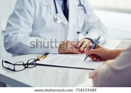 Female patient in office signing a document