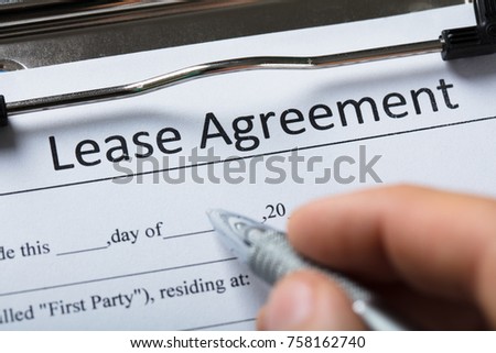 Close-up Of A Human Hand Filling Lease Agreement Form With Pen