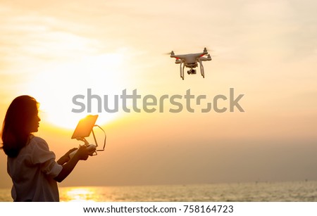 Girl piloted UAV copter drone flying at sunset. drone copter flying with digital camera. UAV Drone with digital camera. Flying camera take a photo and video. drone with camera takes picture of the sky