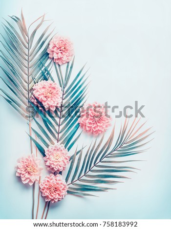 Creative layout with tropical palm leaves and pastel pink flowers on  turquoise blue desktop background, top view, place for text, vertical