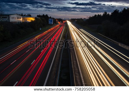 Traffic travels along the M5 past Tewkesbury, Gloucestershire during evening rush hour, leaving traffic light trails