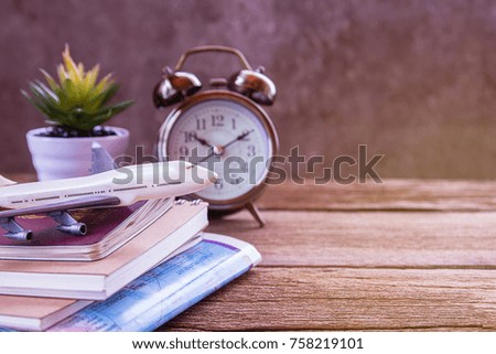 Retro alarm clock,airplane,map and notebook on a wooden table. Photo in retro color image style. Top view with copy space for use.