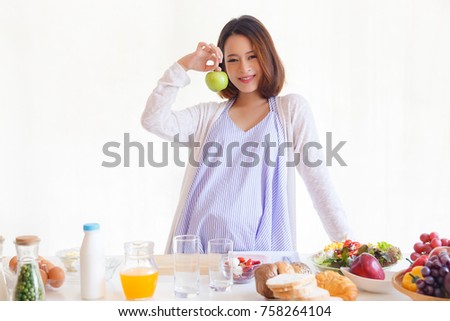 Pregnant beautiful girl holds the green apple. Attractive mother feels relaxed and happy. A charming woman has good health. She takes good care of herself by eating healthy foods. It's good for fetus