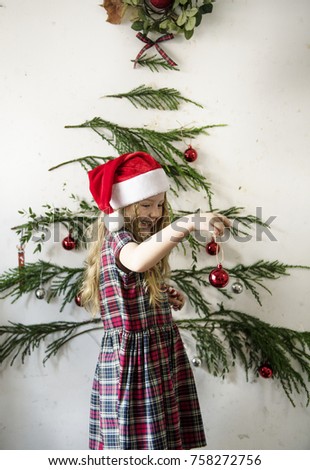 Cute little girl hanging up Christmas ornaments