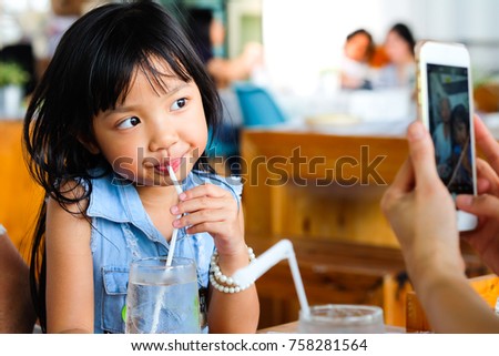 Asian child girl drinking water and poses taking pictures from mobile