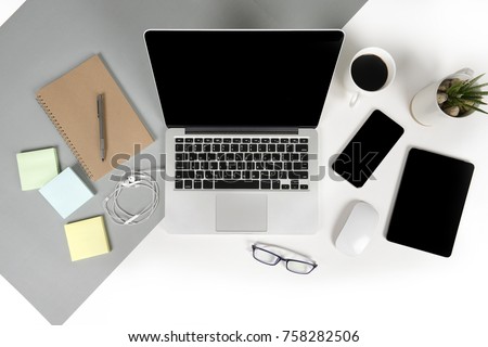 Flat lay photo of Office table with laptop computer, notebook, digital tablet, mobile phone, Pencil, eyeglasses  on modern two tone (white and grey) background. Desktop office mockup concept.