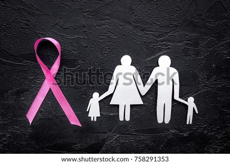 Pink ribbon for breast cancer awareness near paper silhouette of family on black background top view
