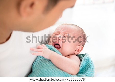 Young father holding crying sleepy cute little newborn baby in his arms with care Royalty-Free Stock Photo #758323078