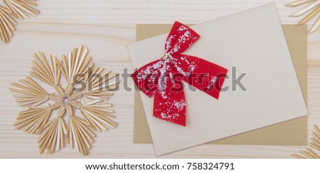 Top view of  blank christmas card with red ribbon bow and handmade snowflakes on a wooden background. Christmas background in natural tones.