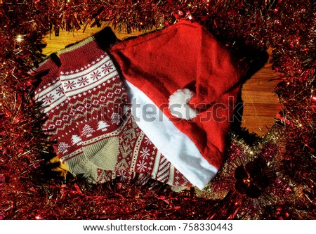 Festive Christmas composition . On a wooden Board are knitted wool socks and cap of Santa Claus. Beautiful and bright Christmas card