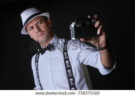 Young stylish man taking funny selfportrait with retro camera. Being silly