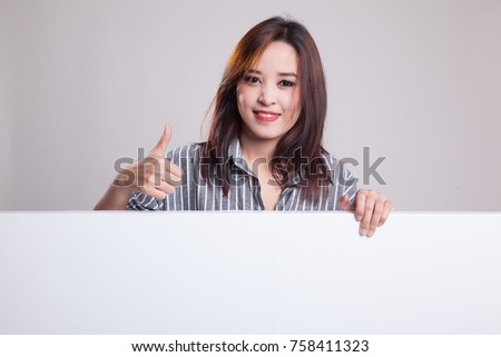 Young Asian woman show thumbs up with blank sign on gray background