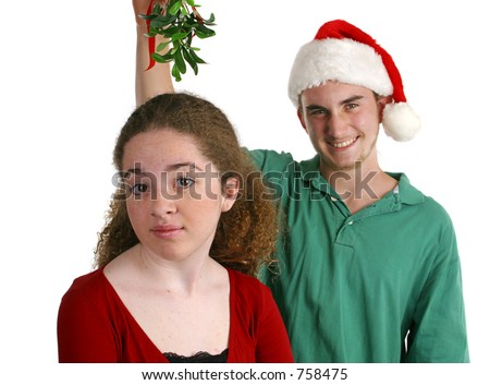 A teen boy holding mistletoe over the head of a teen girl.  She's not interested in him.