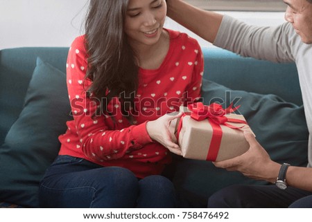 young asian man holding gift for surprise his girlfriend, romantic happy couple sharing gift together on Christmas, happy family concept