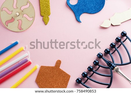 Image of jewish holiday Hanukkah with wooden dreidels (spinning top) , menorah (traditional Candelabra) candles, children's stickers glitter craft on pink background.Top view.
