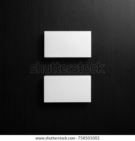 Blank white business cards on black wood background. Mockup for branding identity. Template for graphic designers portfolios. Top view.