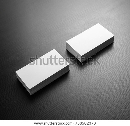 Photo of blank white business cards on black wooden table background. Template for ID. Mockup for branding identity.