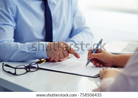 Male boss recommends that his employee sign a contract in the office.