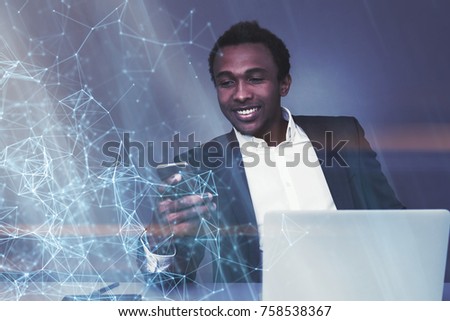 Portrait of a cheerful young African American businessman looking at his smartphone sitting near a laptop. Polygons. Toned image double exposure