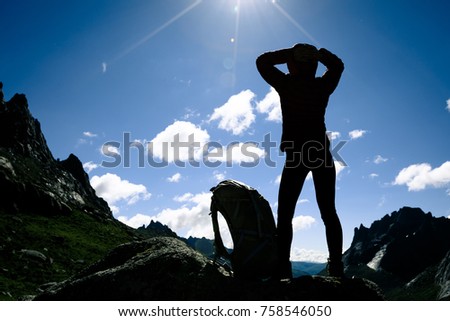 Silhouette of woman with backpack hiking on sunrise mountain top