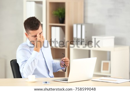 Tired man with laptop in office