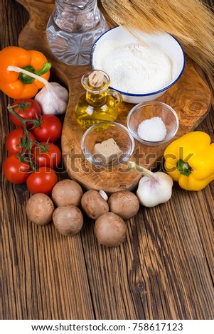 Fresh ingredients for a pizza dough and the pizza topping a wooden board made of olive wood with copy space in the lower part of the picture
