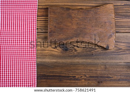 Wooden background with red white checkered cloth and an old cutting board with copy space in the right lower part of the picture