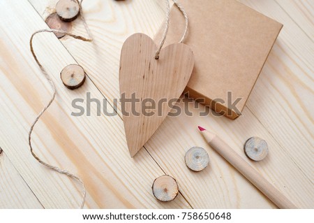 Kraft box and wood heart, mail with pencil on a wooden background. Flat lay, top view photo mock up