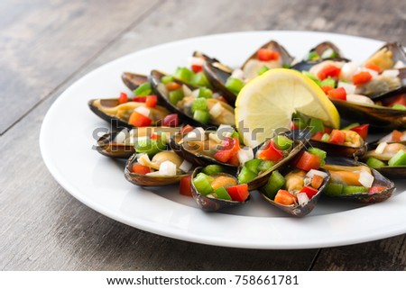 Steamed mussels with peppers and onion on wooden table