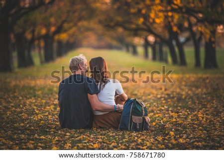 Beautiful romantic couple in orange alley in a park with colorful trees and sunlight. autumn natural background