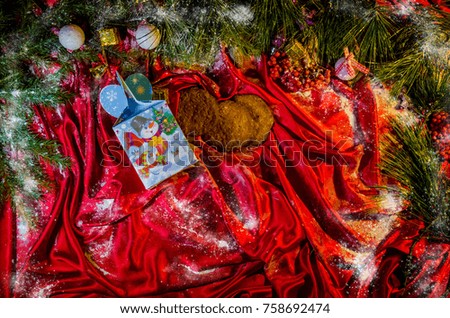 Christmas gift decorated with garlands stands under a Christmas tree with toys on a red background