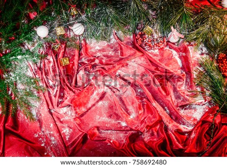 Christmas tree branches and white toy balls on a red background of silk with a rowan berries with sparkling multicolored garland